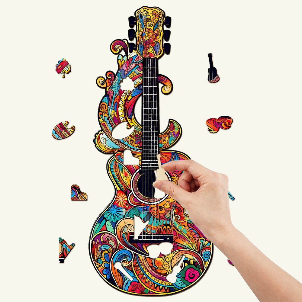 Colorful wooden jigsaw puzzle of a beautiful guitar with pieces being assembled by hand.