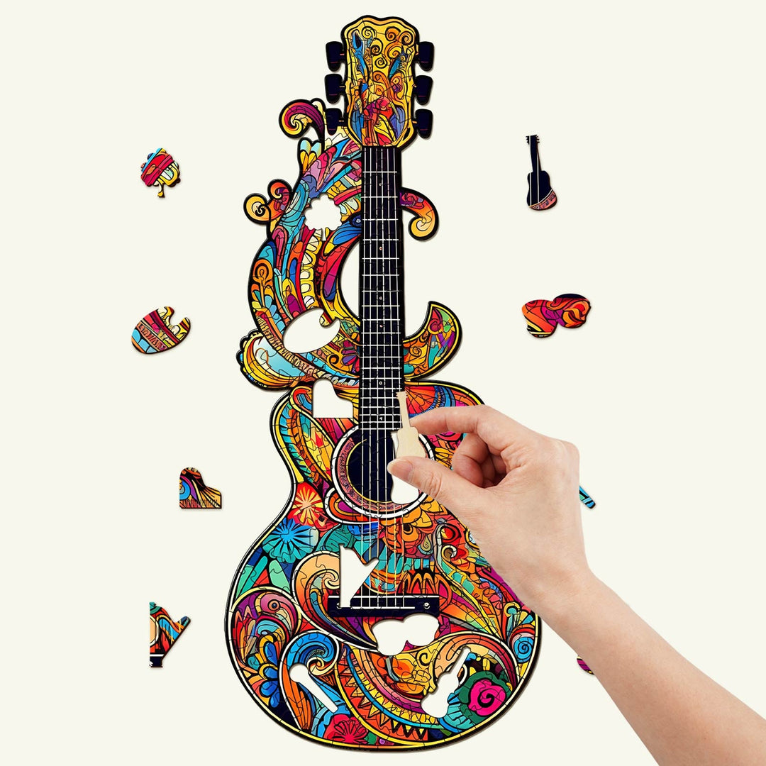 Colorful wooden jigsaw puzzle of a beautiful guitar with pieces being assembled by hand.